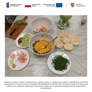 Zdjęcie przedstawia miseczki i talerze z warzywami potrzebnymi do przygotowania sałatki z soczewicy stojące na stole, deskę oraz talerz z waflami ryżowymi.