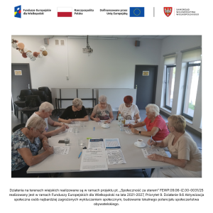 Wnętrze świetlicy wiejskiej w Jasinie. Siedem seniorek siedzi przy dużym kwadratowym stole i rozwiązuje zadania na kartkach papieru.
