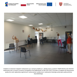 Sześć seniorek ustawionych w półokręgu wykonuje ćwiczenia rozciągające. W pozycji stojącej wyciągają do góry rękę i przechylają tułów w lewą stronę.