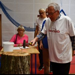 Zdjęcie wykonano podczas olimpiady dla seniorów w Luboniu. Pan w koszulce ze Swarzędzem z młotkiem w ręce.