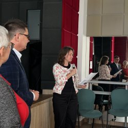 Konferencja poświęcona integracji i wsparciu społeczności romskiej. Dyrektor Centrum i zastępca burmistrza słuchają zapowiedzi prowadzącej.