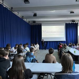 W dużej sali z niebieskimi kotarami przedstawiciel fundacji Varia Posnania opowiada młodzieży o narzędziach partycypacji w szkole i poza nią.