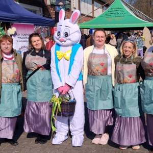 Zdjęcie przedstawia pięć członkiń Koła Gospodyń Wiejskich z zającem maskotką na terenie targowiska w Swarzędzu.