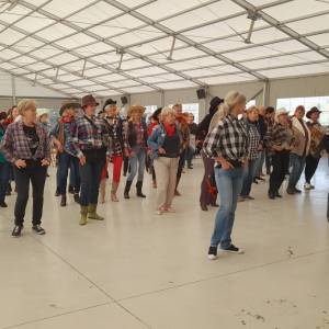 Seniorzy bawią się na scenie pod namiotem w przebraniach w stylu kowbojskim