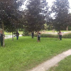 Seniorzy w terenie pozują do zdjęcia obejmując drzewka