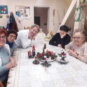 Uśmiechnięte seniorki pozują do zdjęcia przy stole udekorowanym świątecznie