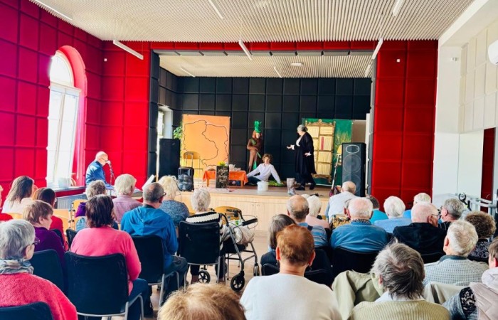 Zdjęcie przedstawia salę wypełnioną ludźmi, oglądających występ teatralny dzieci i dorosłych.