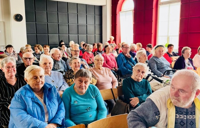 Zdjęcie przedstawia grupę seniorów siedzących na widowni.