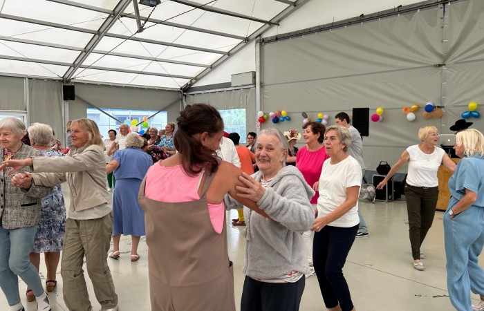 Zdjęcie przedstawia tańczących, rozradowanych seniorów.