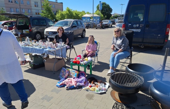 trzy kobiety siedza za stołem z przediotami na sprzedaz